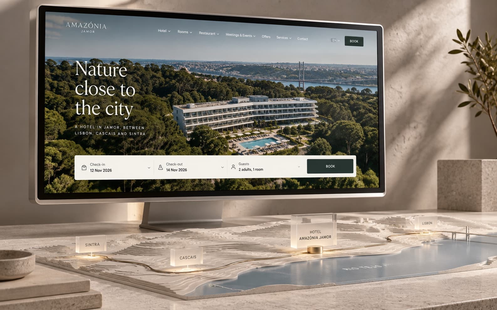 A rendering of the Amazónia Jamor homepage on a desktop monitor, above a relief map placing the hotel between Sintra, Cascais and Lisbon.